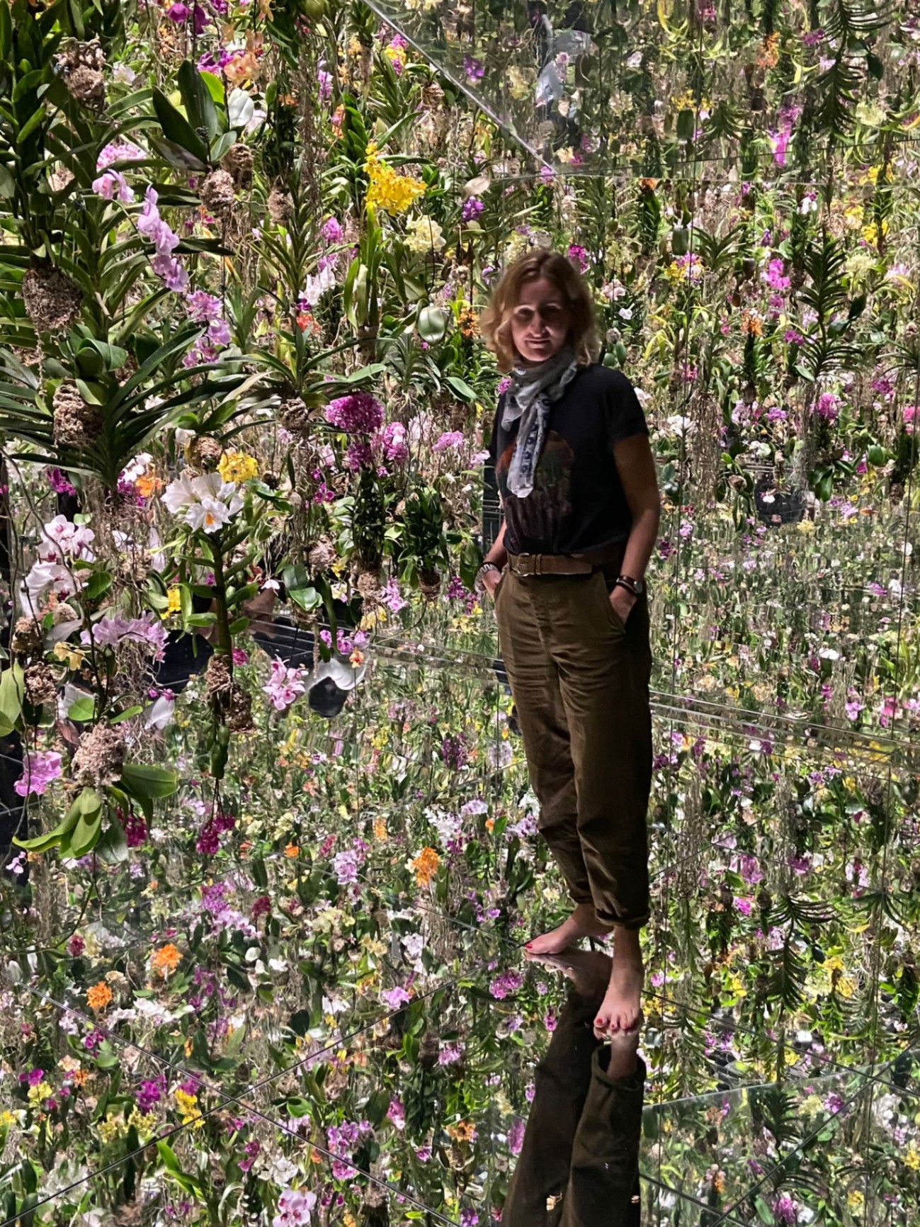 Juliette Neouze in an immersive installation of suspended orchids, mirror on the floor